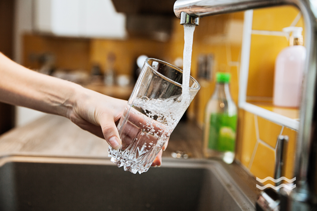 Hand holding glass under a tap with running water