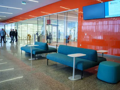 Turquoise lounge couches against a bright orange wall in the main lobby area