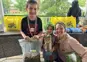 little boy with medal beside little girl in gecko costume beside her mom
