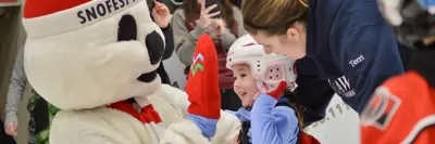 Snofest Pete mascot high-fives a child skating at a City arena
