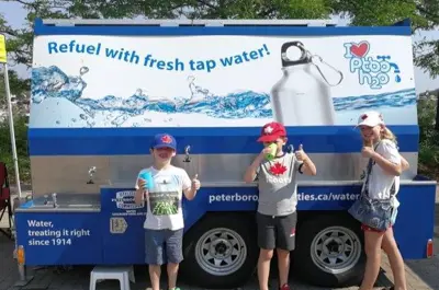 Three children standing next to a mobile water station