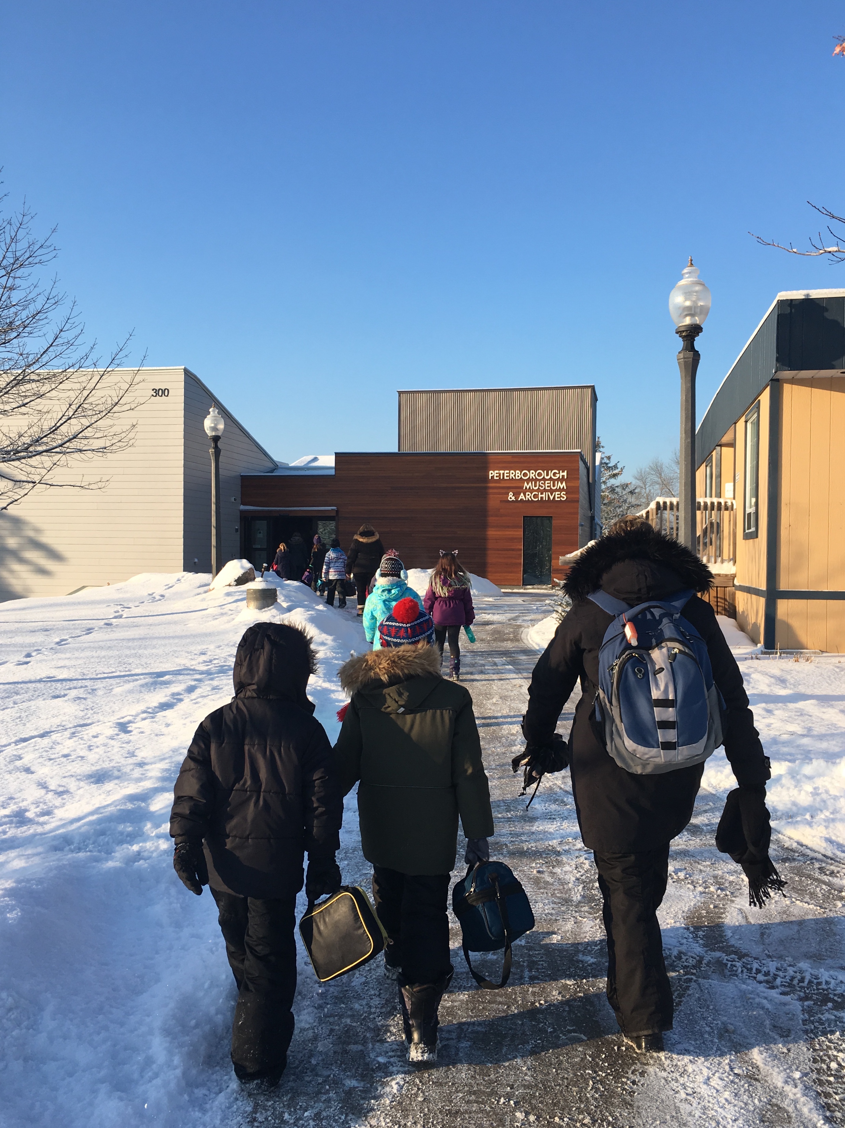 Children walking into museum along a walkway with snow covered lawn