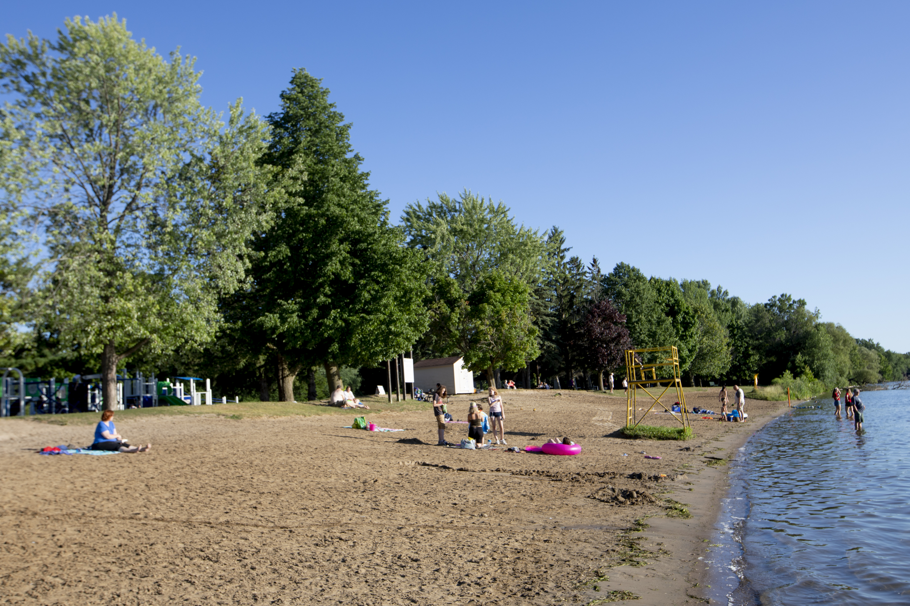 People enjoying Beavermead Beach on a sunny summer day