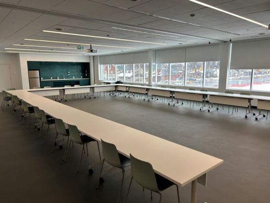 Rental room set up with long rectangular tables in a U shape and chairs