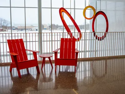 Two bright orange lounge chairs and the artwork Resonant Harmony in the atrium