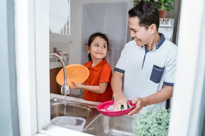 An adult and child washing dishes