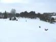 snowy toboggan hill at the disc golf park with a a toboggan rider